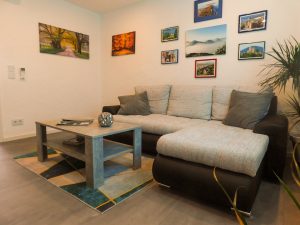 zu sehen ist das Sofa mit Wohnzimmertisch und einige Bilder an der Wand.
