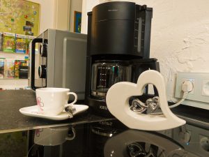 Nahaufnahme Küche: Zu sehen ist eine Kaffeemaschine und eine Kaffeetasse auf einem Unterteller. 
